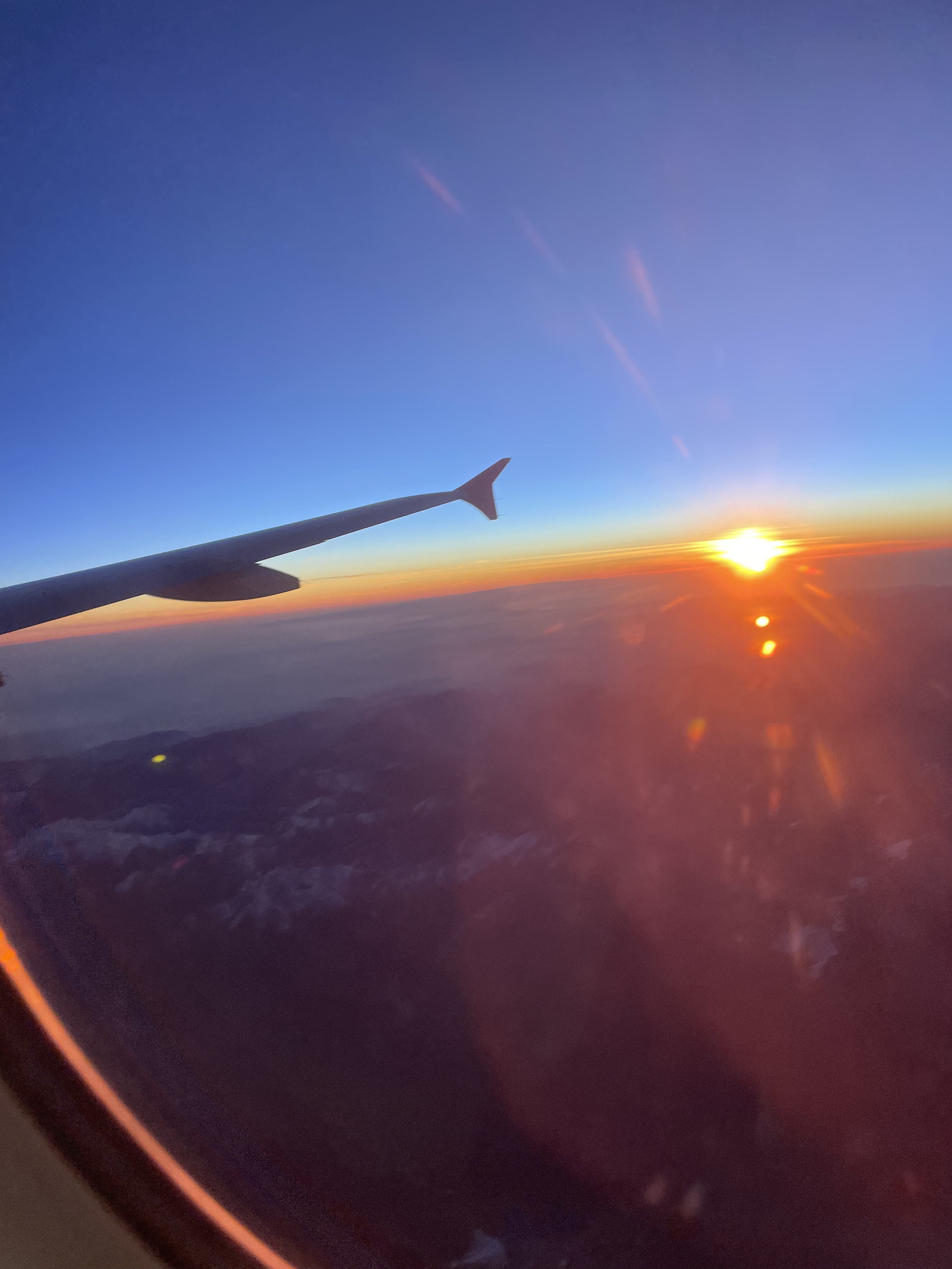 Sonnenuntergang mit Regenbogen vom Flugzeug